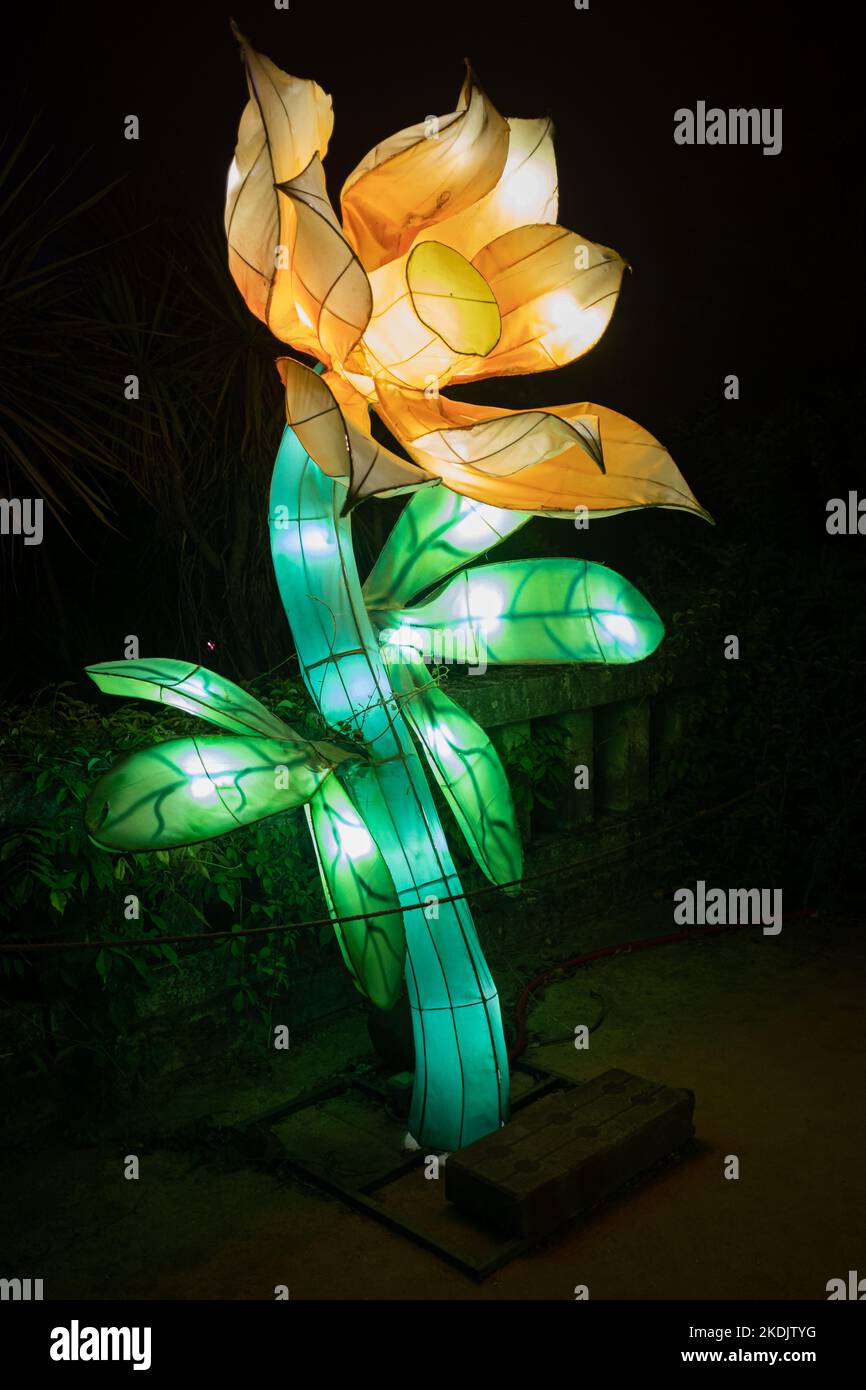 Kunstvolle handgefertigte Blumen, die in der Nacht mit Neonlichtern in einem Nachtgarten leuchten Stockfoto