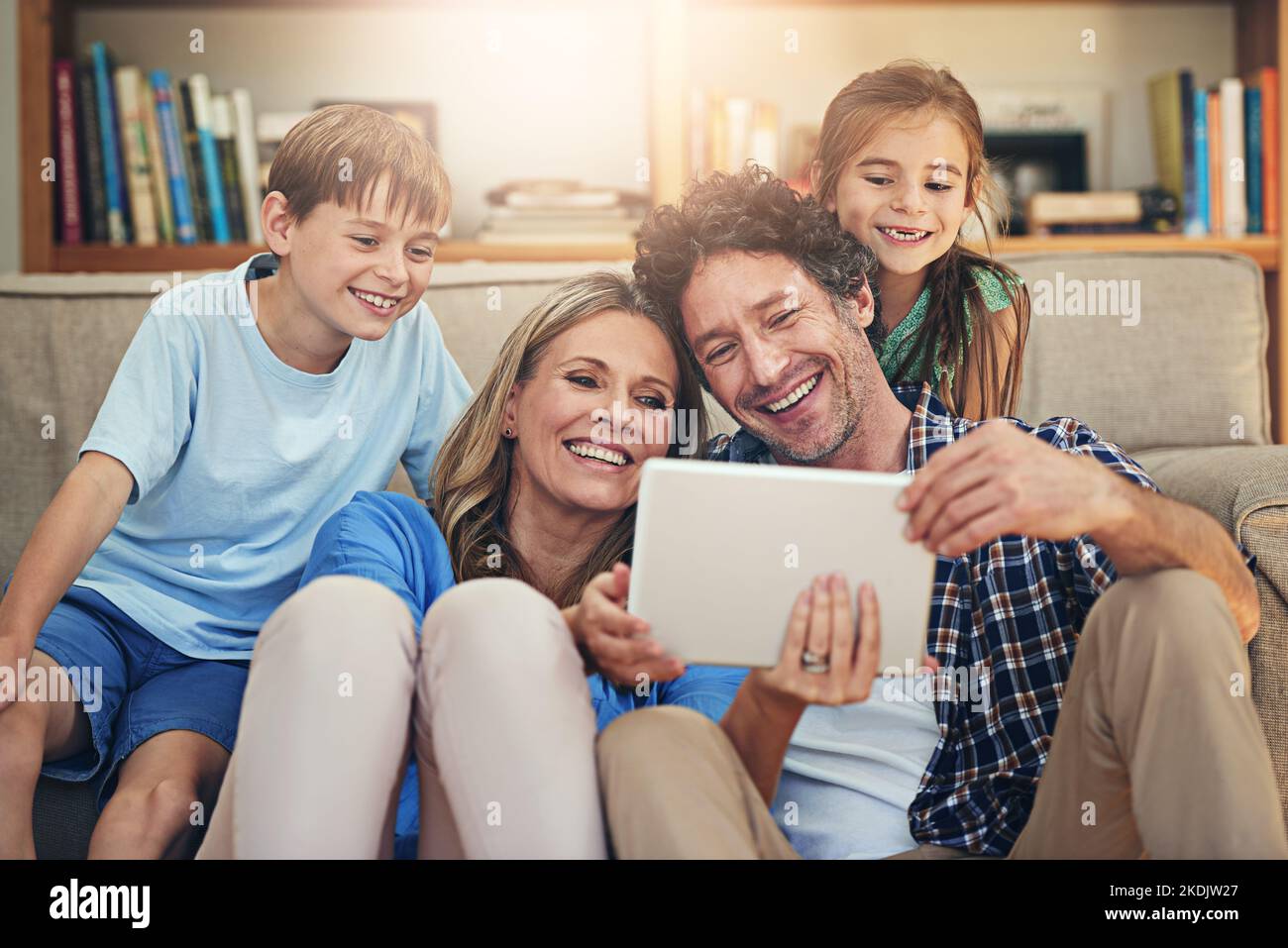 Aus Familienzeiten wird Bildschirmzeit. Eine glückliche Familie, die zu Hause ein digitales Tablet nutzt. Stockfoto