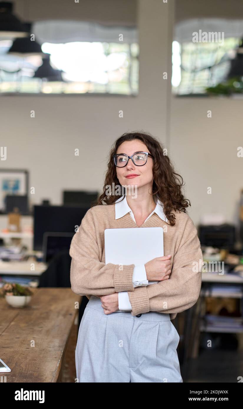 Junge verträumte professionelle Geschäftsfrau, die im modernen Bürodenken steht. Stockfoto