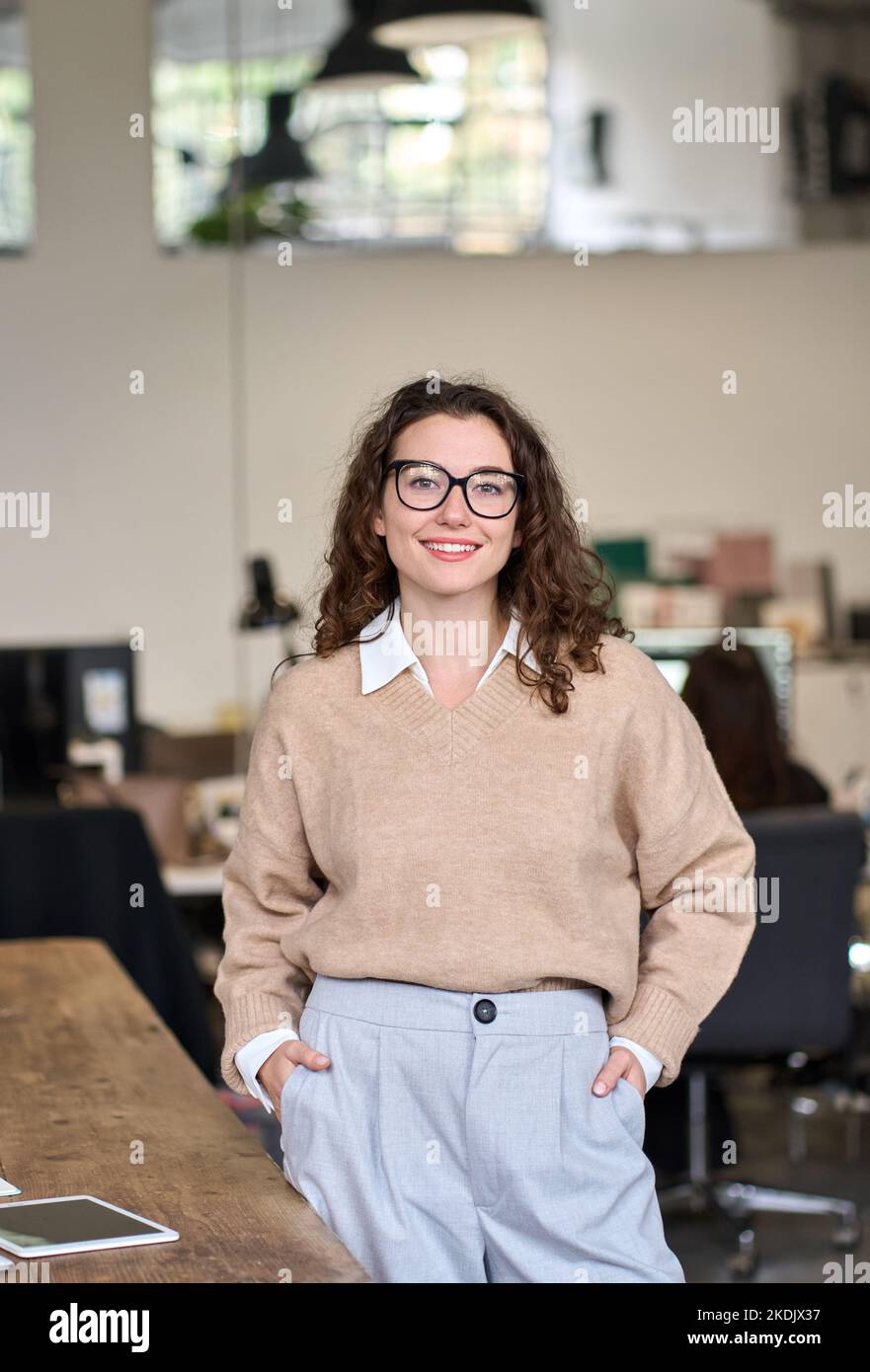 Junge glückliche professionelle Geschäftsfrau im Büro stehend, vertikales Porträt. Stockfoto