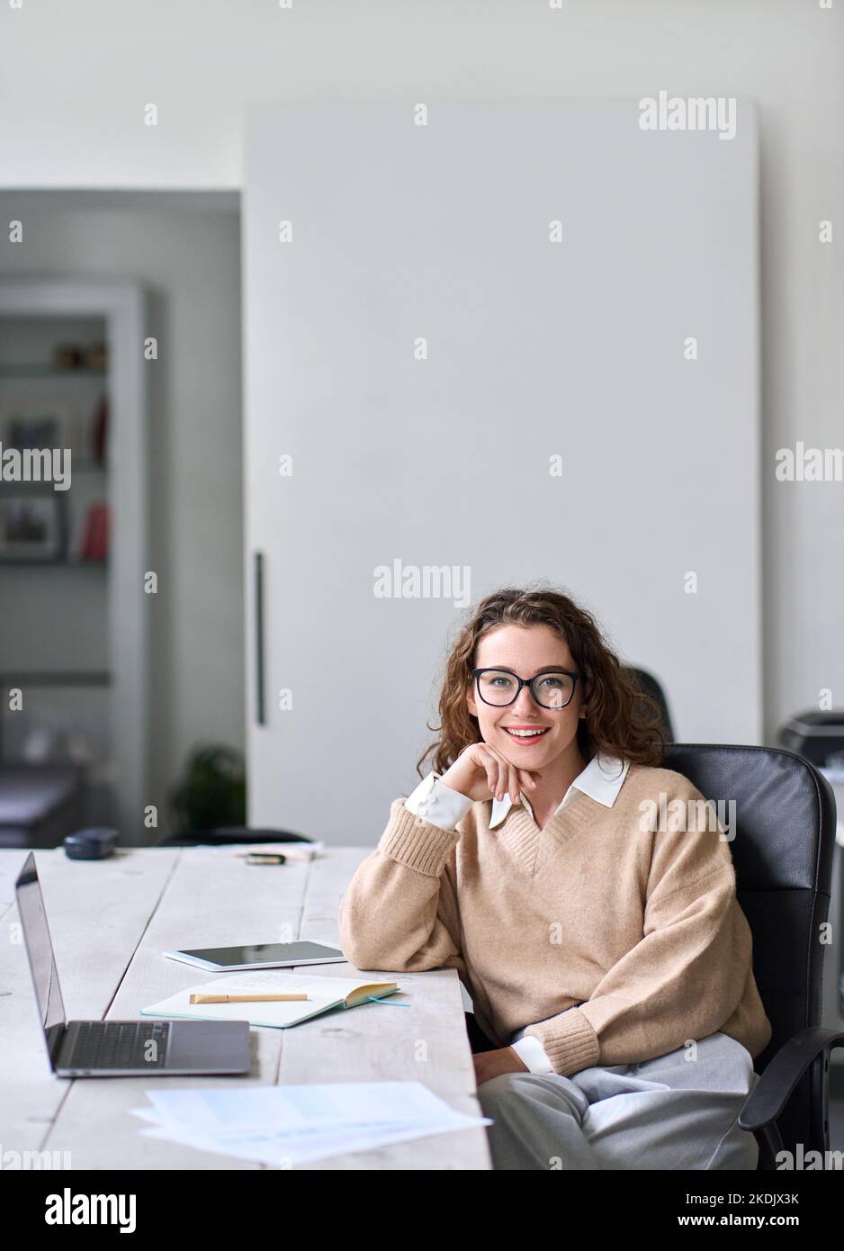 Junge glückliche professionelle Geschäftsfrau sitzt am Schreibtisch, Porträt. Stockfoto