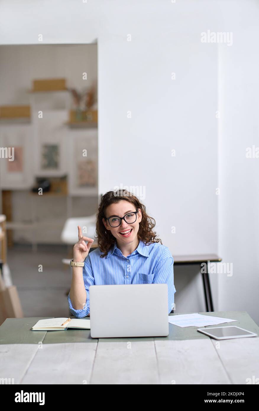 Glückliche Geschäftsfrau oder Studentin, die an einem Laptop arbeitet, zeigt auf, dass sie eine Idee hat. Stockfoto