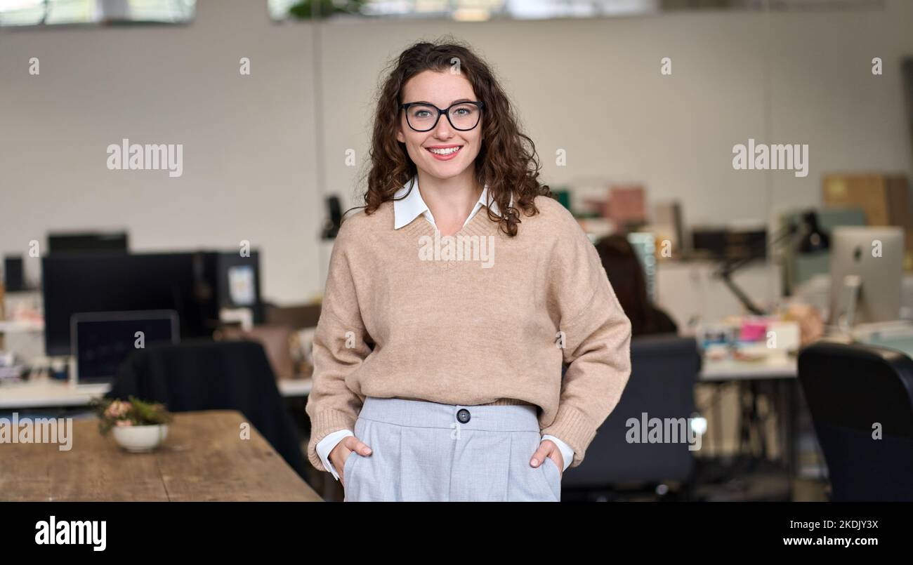 Junge glückliche professionelle Geschäftsfrau im Büro stehend, Porträt. Stockfoto