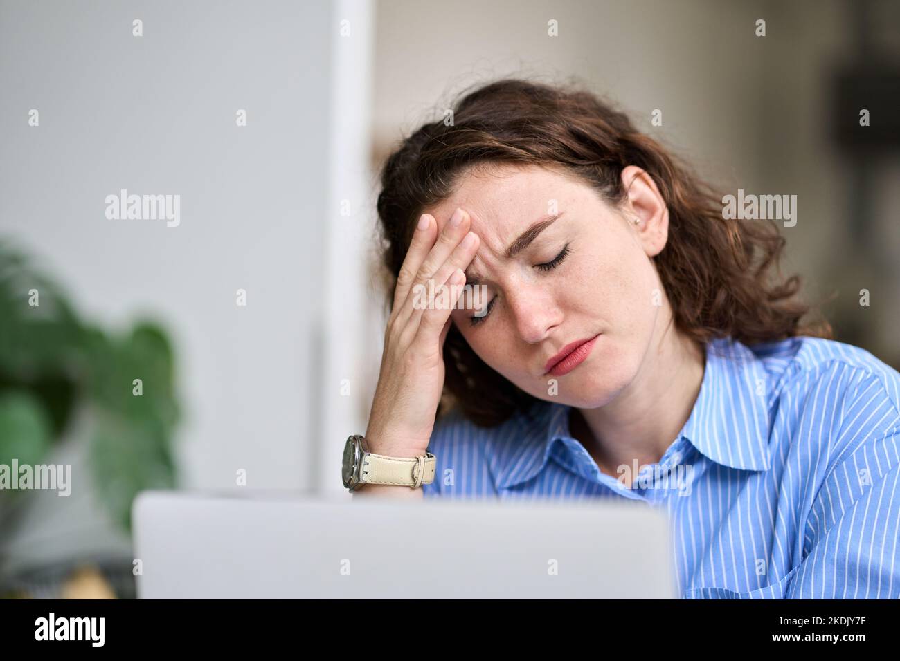 Müde junge Geschäftsfrau, die den Kopf berührt und Kopfschmerzen fühlt, Müdigkeit bei der Arbeit. Stockfoto