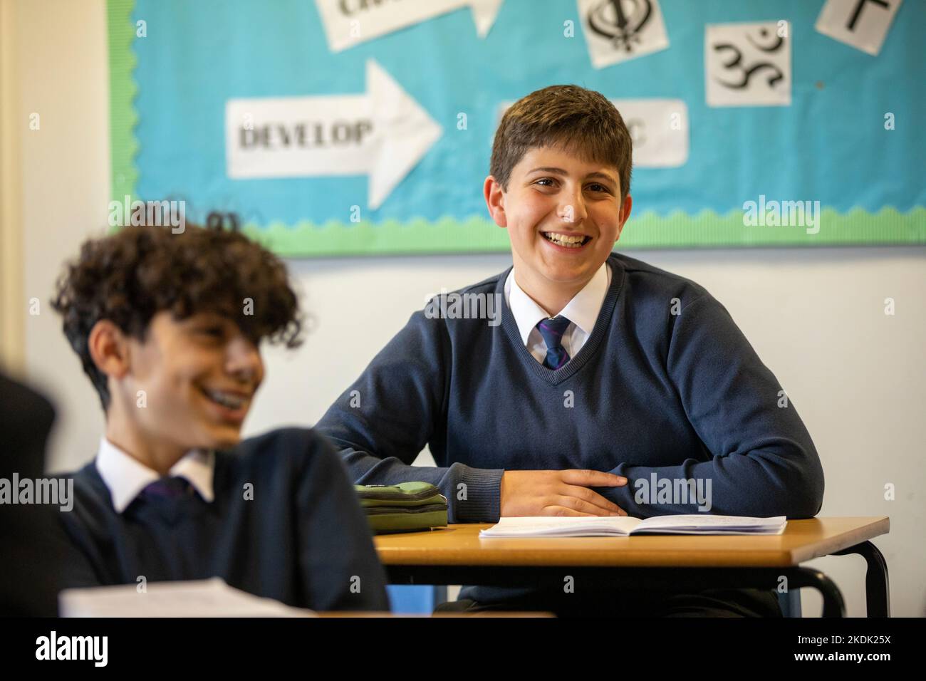 Zwei Jungen, die lächeln, während der Unterrichtsstunde an einer britischen Sekundarschule. Stockfoto