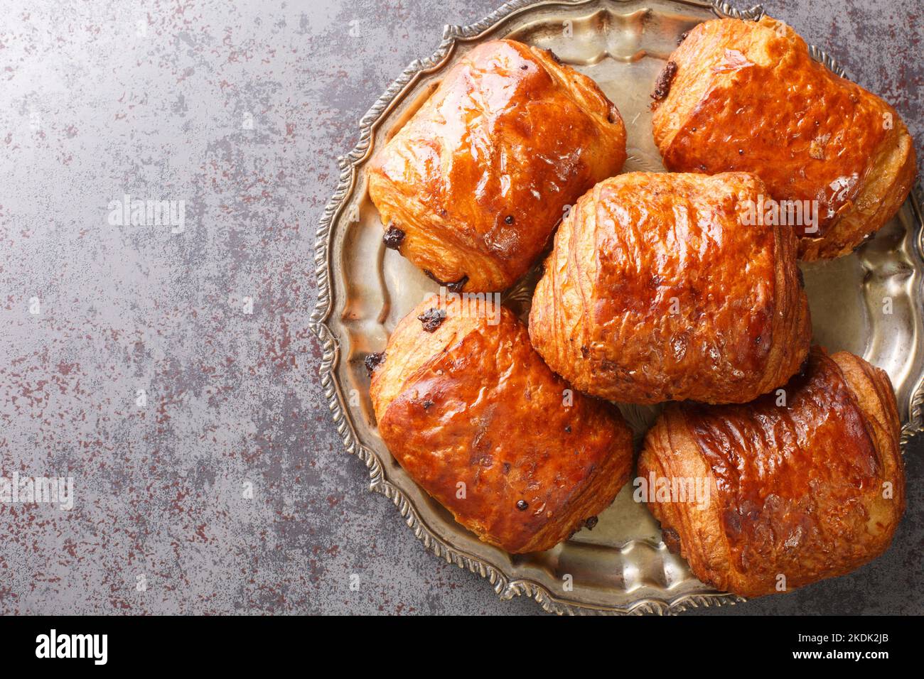 Hausgemachte Schokoladen-Croissants Pain au Chocolat aus der Nähe auf dem Teller auf dem Tisch. Horizontale Draufsicht von oben Stockfoto