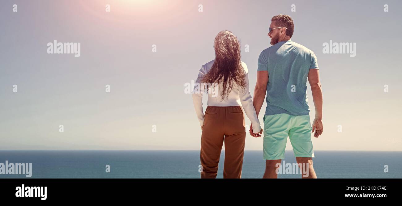 Banner eines verliebten Paares, das sich am Strand umarmt, junge Familie, die weit schaut. Reiseurlaub. Glücklicher Mann und Frau halten die Hände. Ein Paar geht weiter Stockfoto