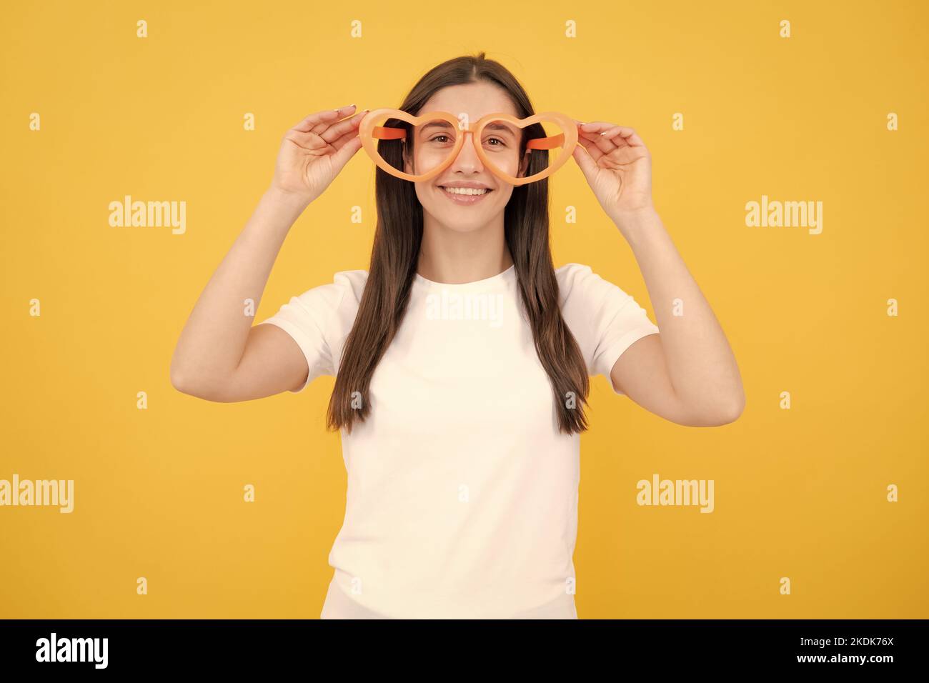 Mädchen mit herzförmigen Gläser lustig und lächelnd auf gelben Studio-Hintergrund. Stockfoto