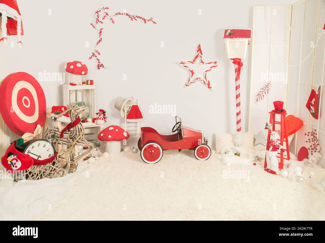 Metall-Auto in einer Weihnachtsdekoration zusammen mit anderen roten und weißen Objekten. Stockfoto