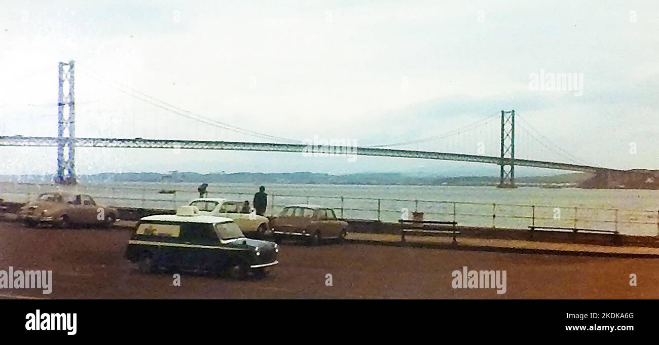 Eine alte Momentaufnahme fotografierte alte Fahrzeuge, die in der Nähe der vierten Straßenbrücke bei South Queensferry geparkt waren, kurz nach ihrer Öffnung für den Verkehr im Jahr 1964, als es die längste Hängebrücke der Welt außerhalb der Vereinigten Staaten war, ursprünglich eine Mautbrücke, aber die Mautgebühren wurden 2008 aufgegeben Stockfoto