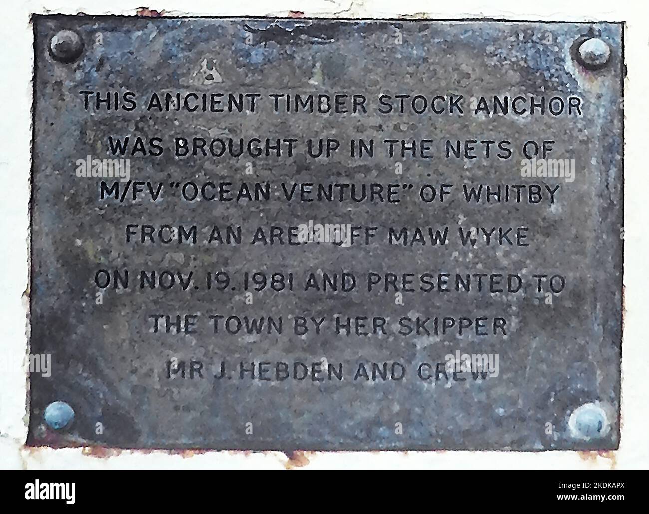 Plakette am Tate Hill Pier, Whitby, Yorkshire, neben einem Anker. Dieser alte Holzlageranker wurde am 19.. November 1981 in den Netzen des Ocean Venture von Whitby aus einem Gebiet vor Maw Wyke aufgezogen und der Stadt von ihrem Skipper J. Hebden und der Besatzung überreicht. Stockfoto