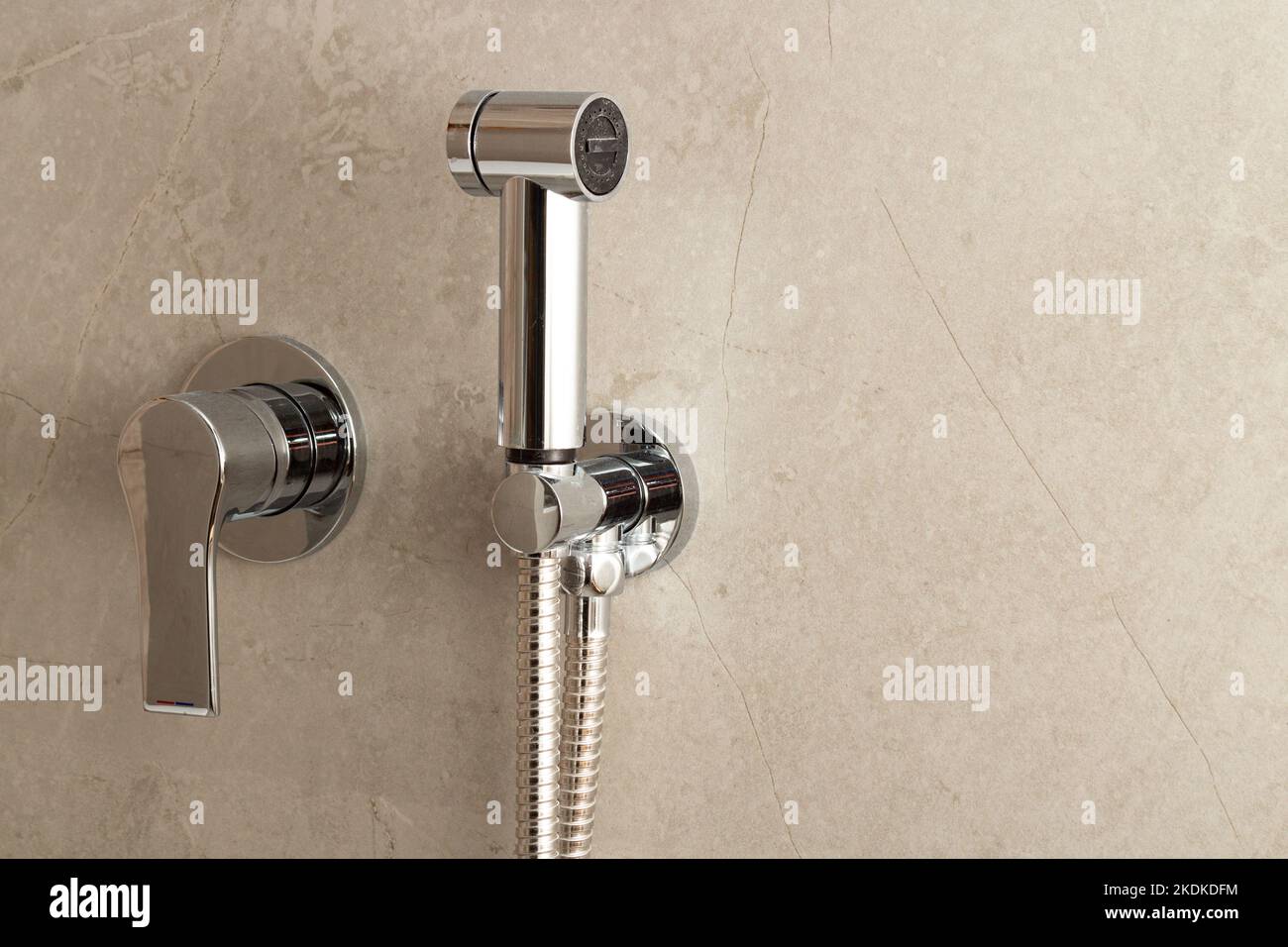 Manuelle Bidet-Sprühdüse aus Edelstahl an der Toilettenwand Stockfoto