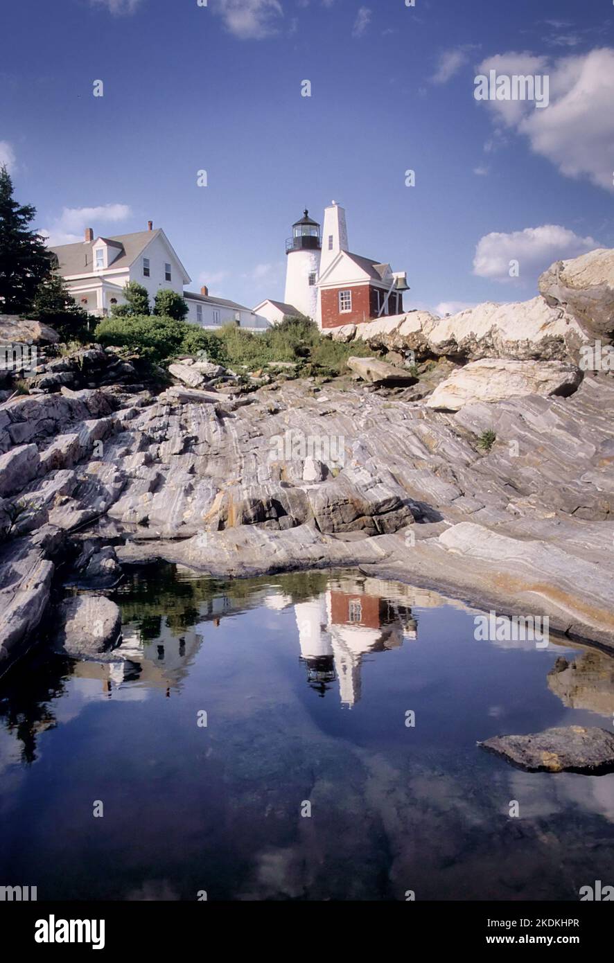 Der Leuchtturm Pemaquid spiegelt sich in einer nahe gelegenen Pfütze wider, die in dem festen Granit, der die Küste von Maine bildet, gefangen ist. Stockfoto
