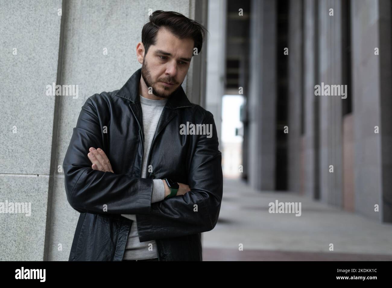 Der herabhängende Mann in einem depressiven Zustand mit gekreuzten Armen auf seiner Brust steht und schaut nach unten Stockfoto