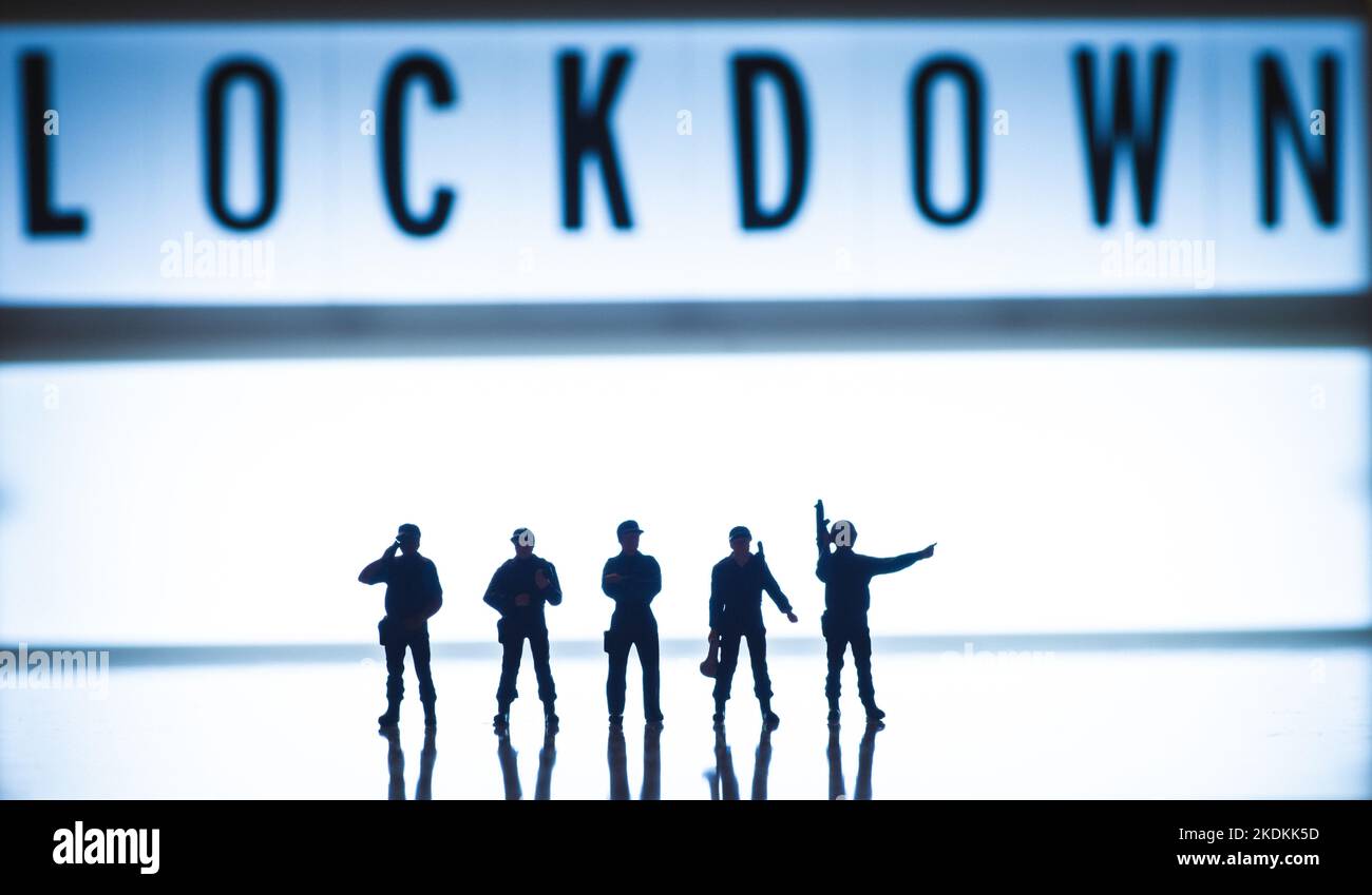 Bilder des Lockdown-Konzepts - niedrige blaue Farbtöne Miniatur Spielzeugfiguren der Sicherheitskräfte - Silhouette von Armee oder Polizei. Stockfoto