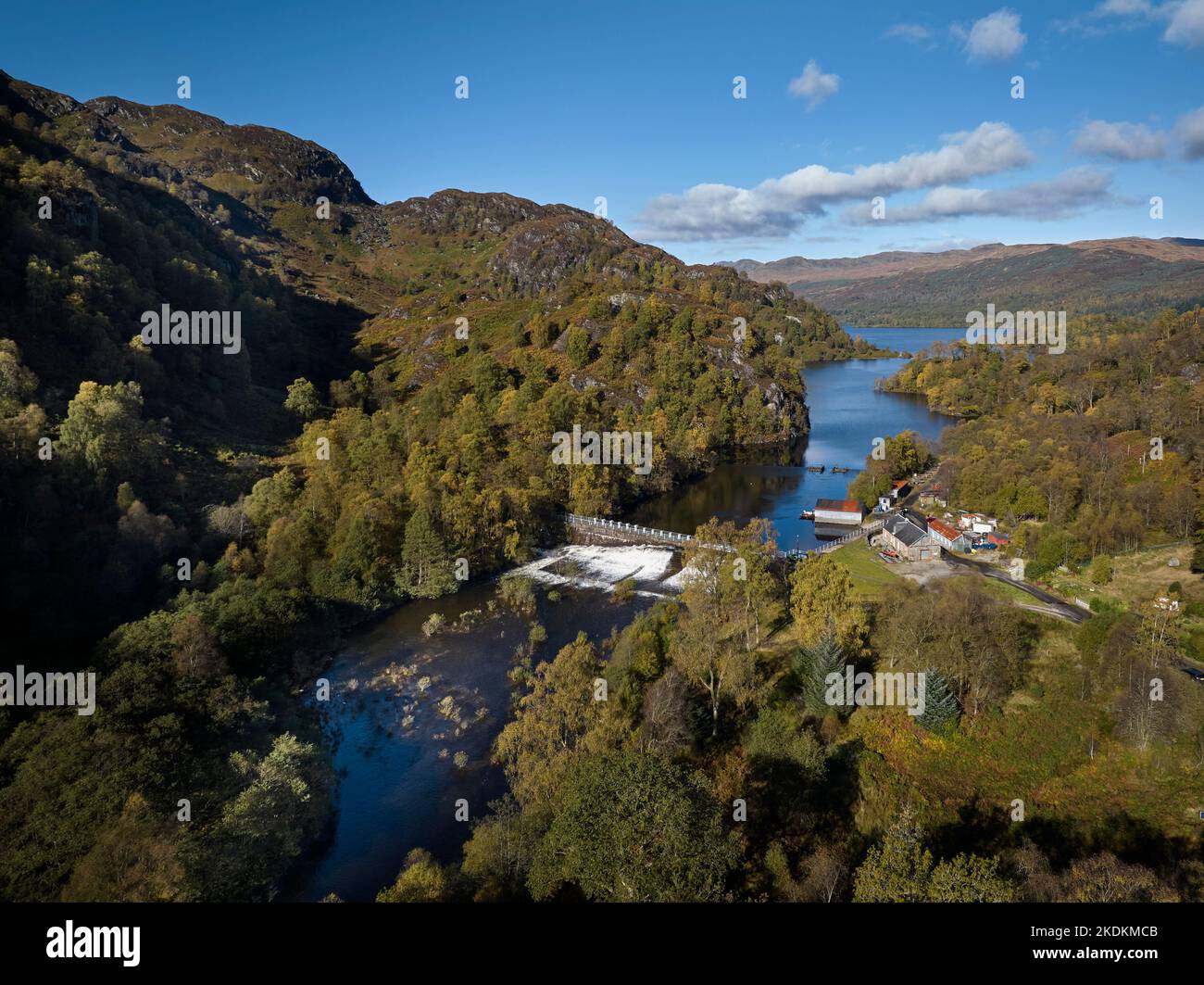 Luftaufnahme des Damms am Loch Katrine mit mehreren geöffneten Schleusentoren und Wasserfällen, die an einem wunderschönen Herbsttag die Fischleiter hinunter stürzen. Stockfoto