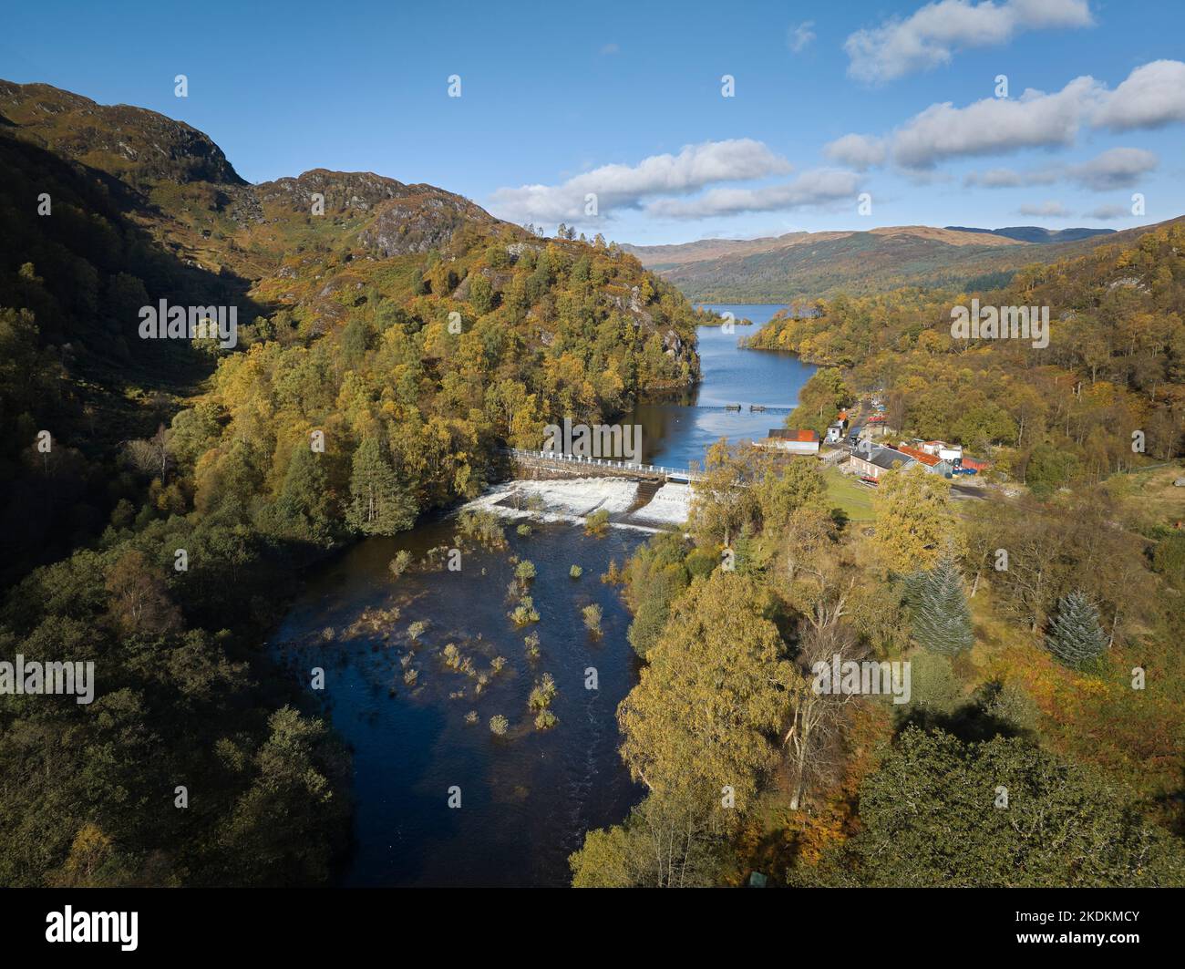 Luftaufnahme des Damms am Loch Katrine mit mehreren geöffneten Schleusentoren und Wasserfällen, die an einem wunderschönen Herbsttag die Fischleiter hinunter stürzen. Stockfoto