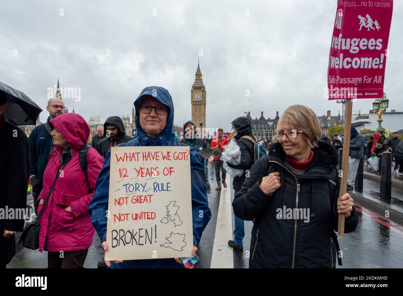 Eine Protesterin mit dem Plakat „12 Jahre Tory-Herrschaft, was haben wir?“ mit einer anderen Frau und dem Plakat „Refugees Welcome“ vor Big Ben, London. Stockfoto