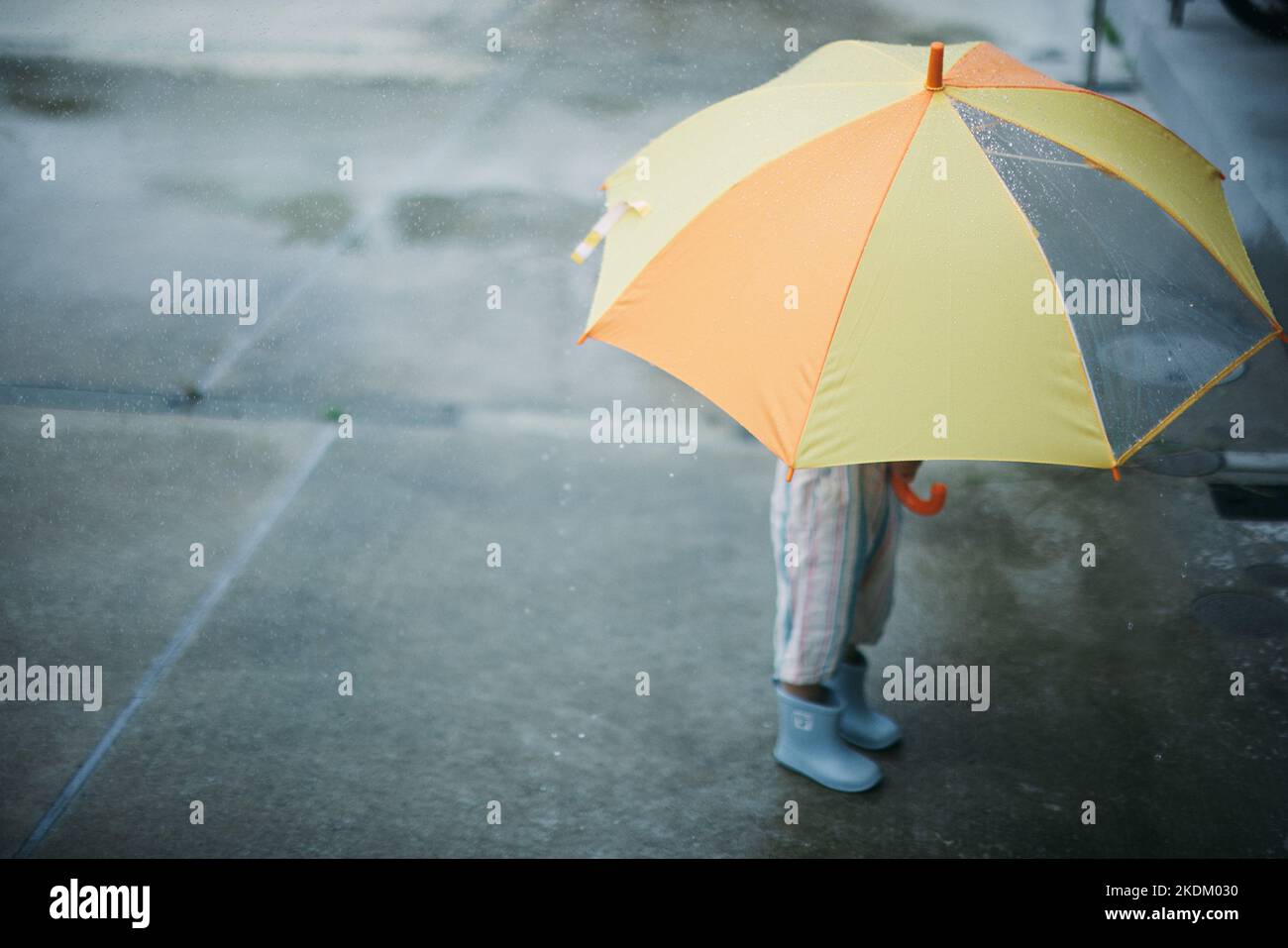 Japanisches Kind, das an einem regnerischen Tag draußen spielt Stockfoto