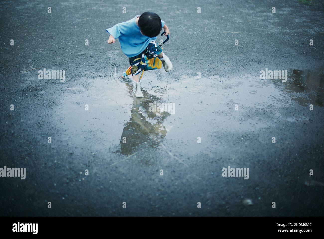Japanisches Kind, das an einem regnerischen Tag draußen spielt Stockfoto