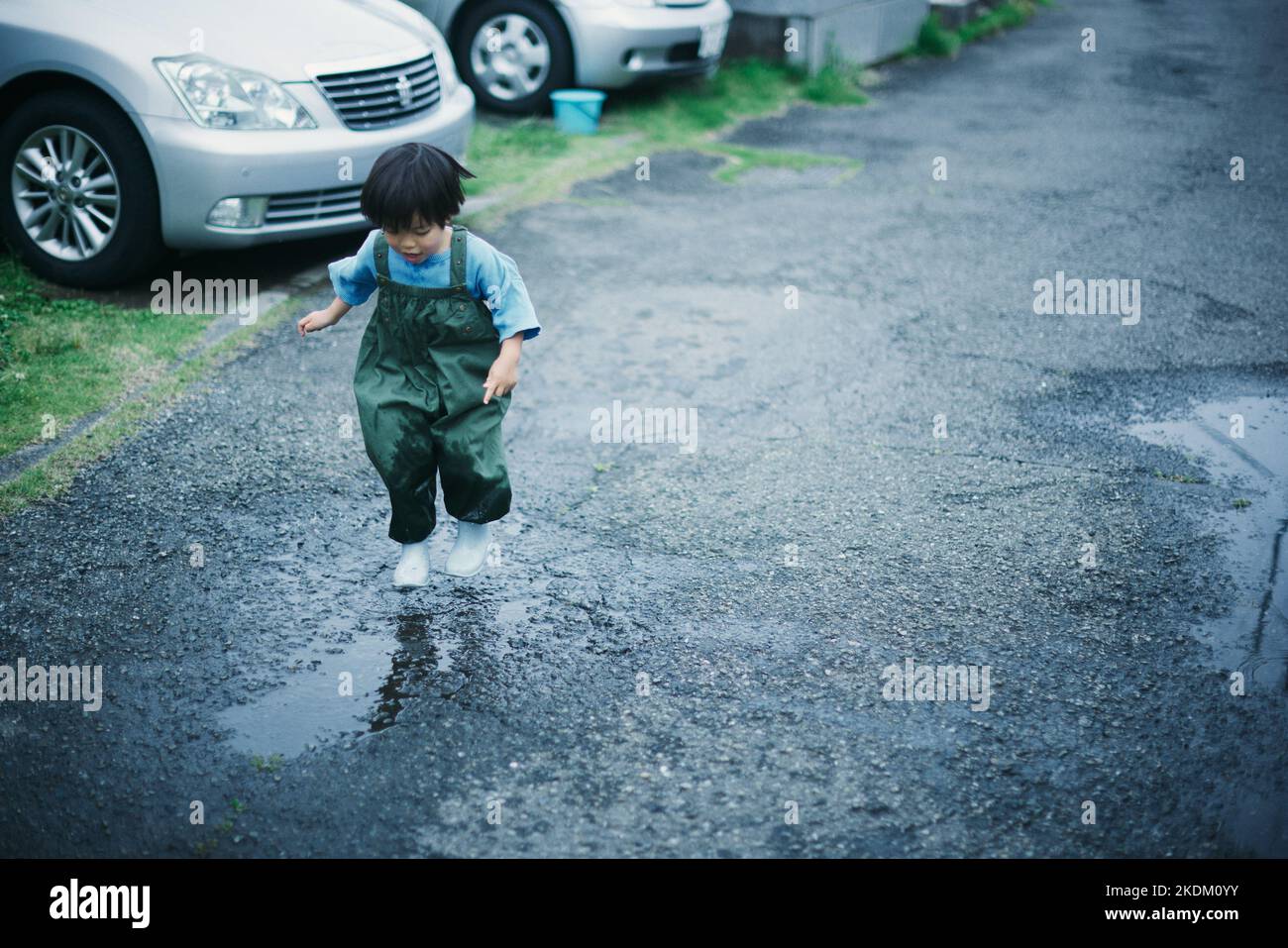 Japanisches Kind, das an einem regnerischen Tag draußen spielt Stockfoto