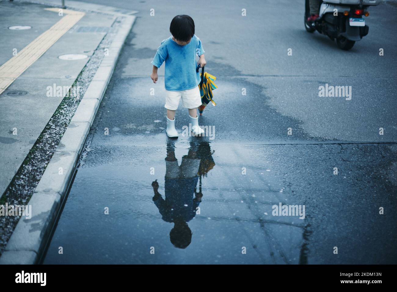 Japanisches Kind, das an einem regnerischen Tag draußen spielt Stockfoto