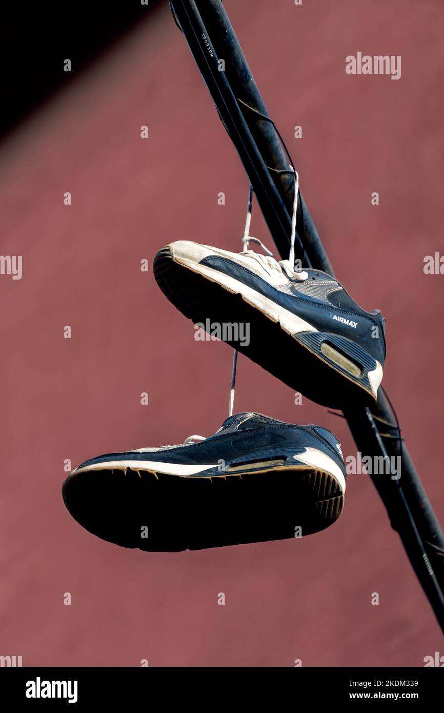 Barcelona, Spanien - 24. Oktober 2022: Schuhe hängen an einem Kabel, das die Straße eines Viertels überquert, gemeinsamer Streich in Vorstadtvierteln Stockfoto