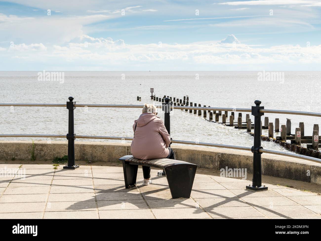 Die einstehende Dame saß auf der Bank und schaute auf das Meer Lowestoft Seafront Parade suffolk 2022 Stockfoto