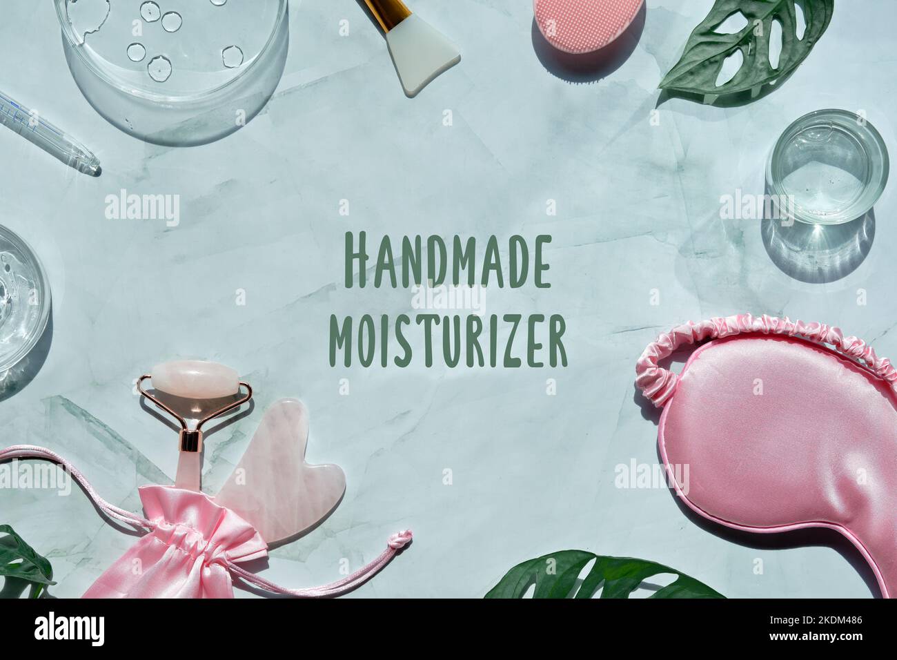 Gesichtswalze aus rosa Stein. Anti-Age-Gesichtsmassage für natürliche Lifting-Behandlung. Wellness flach auf Minzgrün mit Monstera-Blättern. Handtuch, schlafen Stockfoto