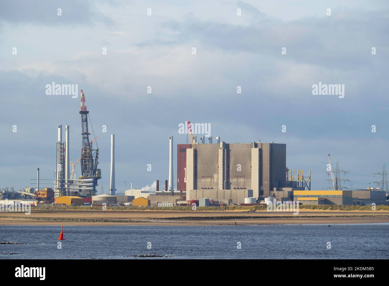 Kran in der Able-Recyclinganlage neben dem Kernkraftwerk Hartlepool, der große Turbinenschaufeln eines Windparks auf ein Installationsschiff lädt Stockfoto