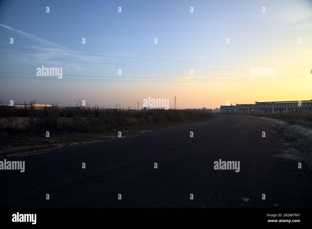 Leere Straße mit verlassenen Lagerhäusern und Pylonen bei Sonnenuntergang Stockfoto