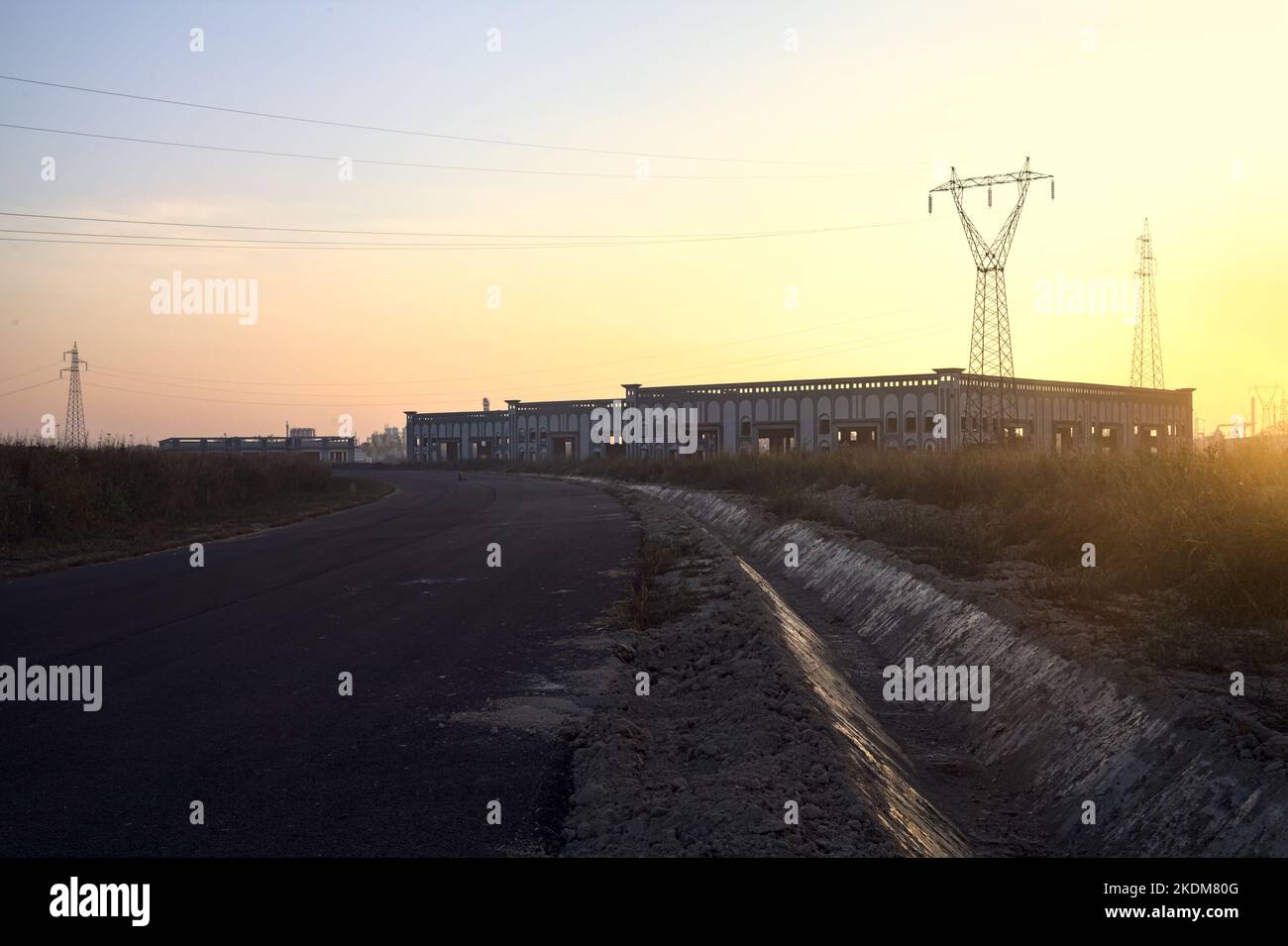 Leere Straße mit verlassenen Lagerhäusern und Pylonen bei Sonnenuntergang Stockfoto