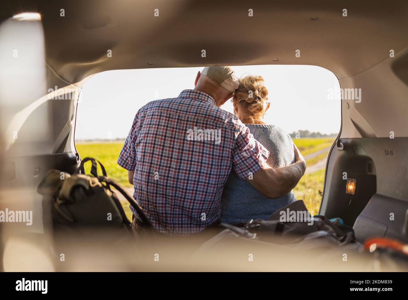 Glückliches Seniorenpaar, das in freier Wildbahn im offenen Kofferraum sitzt Stockfoto