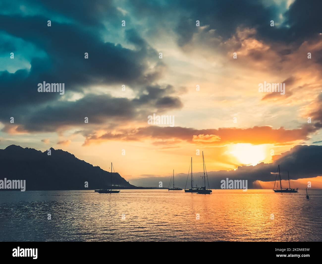 Majestätische Yacht Tour Reise Landschaft. Dramatischer Sonnenuntergang in der tropischen Insellagune. Yachten Silhouette gegen leuchtend orange Sonne und blauen Wolken Himmel. Wundervolle, malerische Szene. Französisch-Polynesien Stockfoto