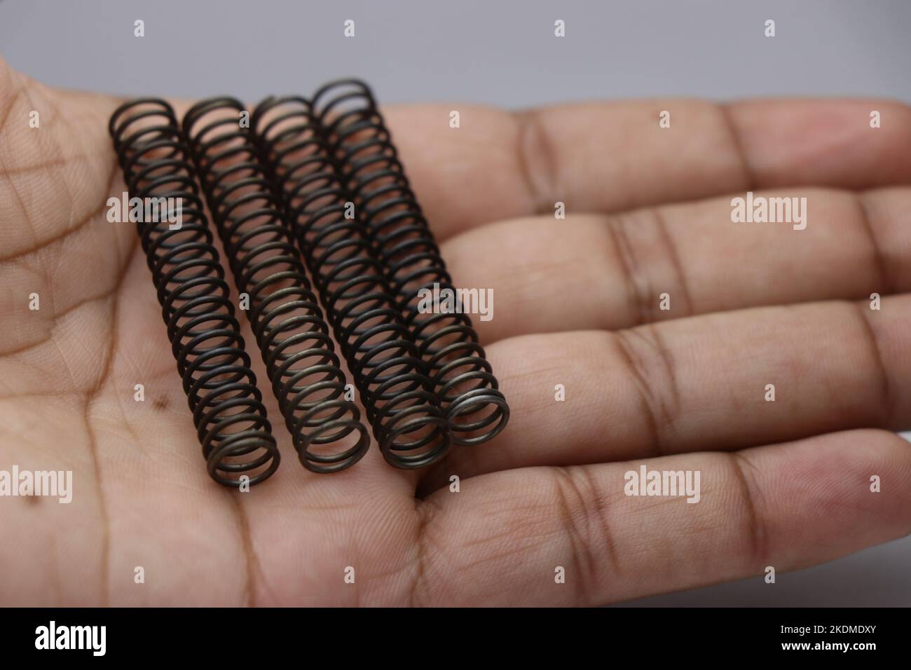 Vier Druckfedern aus Stahl in der Hand gehalten. Metallfedern als Austausch von mechanischen Teilen Stockfoto