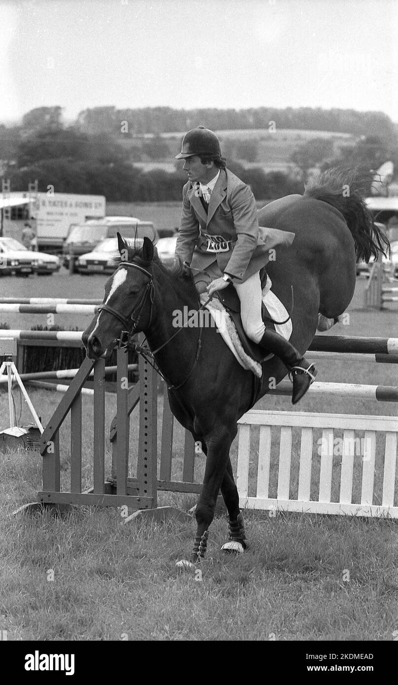 1970s, Historica, Grafschaft Show, Reiten, ein männlicher Reiter auf seinem Pferd springen einen Zaun oder Hindernis in einem Springreiten Veranstaltung auf einem Rasen, England, Großbritannien. Stockfoto