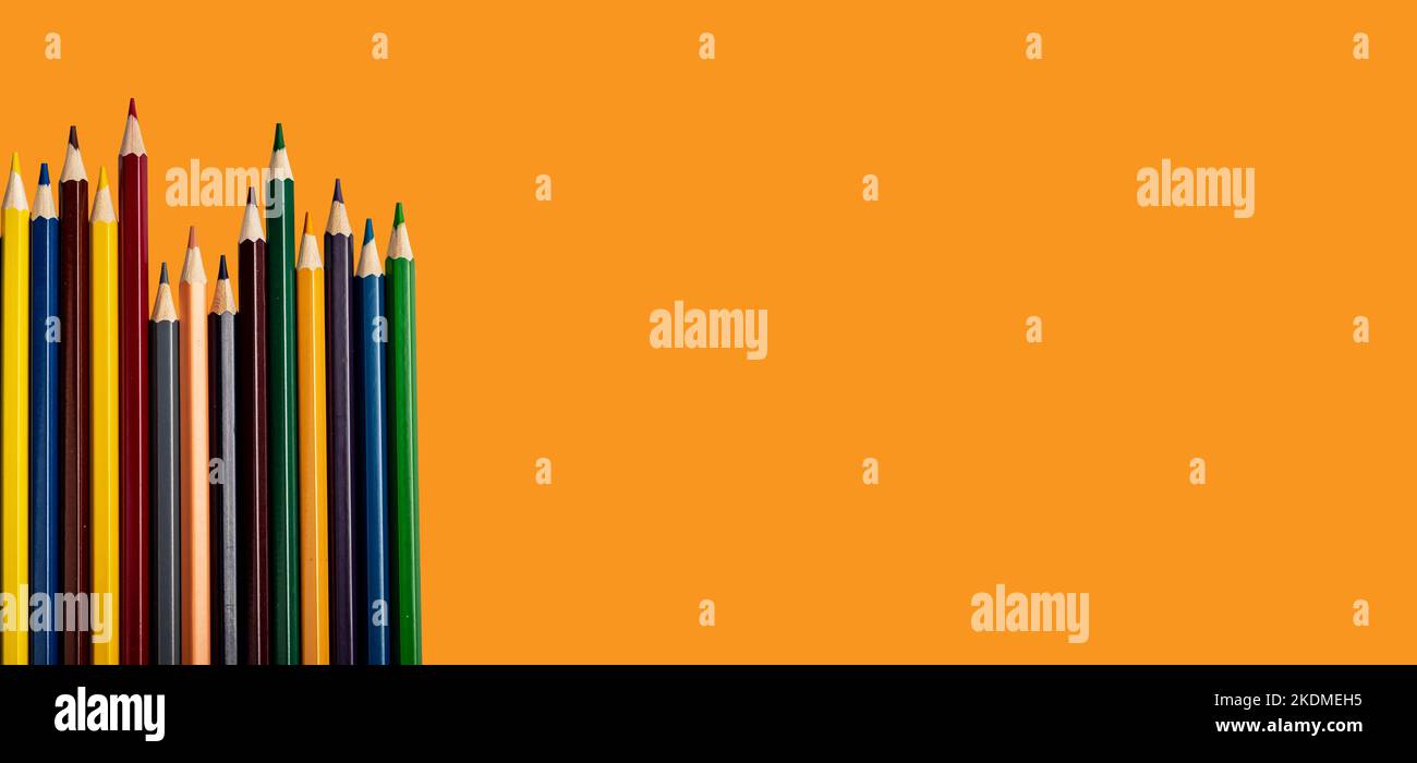 Buntstifte auf orangefarbenem Hintergrund. Schulbanner mit Platz für Text. Hochwertige Fotos Stockfoto