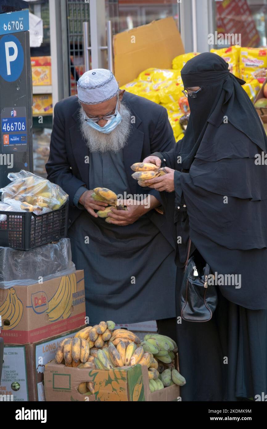 Ein muslimisches Paar kann Bananen an einem Stand im Freien im Apna Supermarkt in der 73ed Street in Jackson Heights, Queens, New York City kaufen. Stockfoto