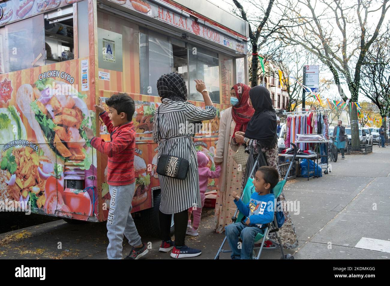 Muslimische Frauen in Hijabs und ihre Kinder kaufen in einem Halal-Lastwagen Lebensmittel ein. In Jackson Heights, Queens, New York City. Stockfoto