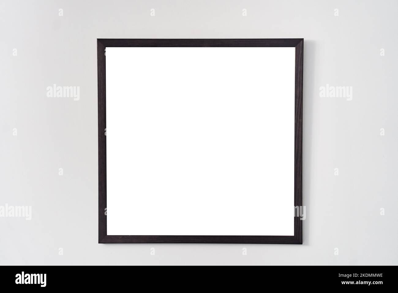 Ein leerer quadratischer Bilderrahmen mit schwarzem Rand, der an einer weißen Wand hängt Stockfoto