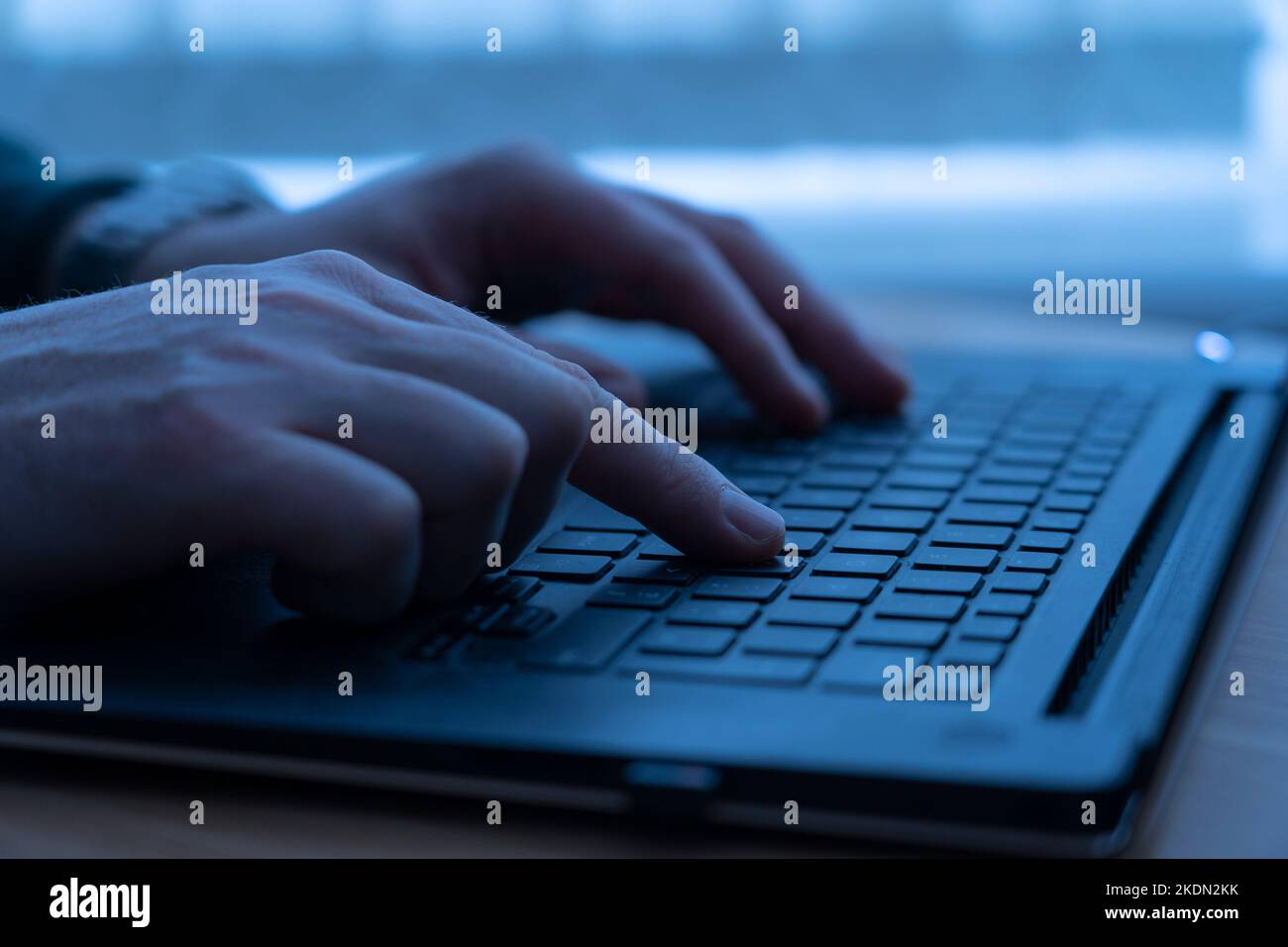 Ein Mann mittleren Alters, der auf einer Laptop-Tastatur tippt. Konzept: Einsamkeit, Online-Mobbing, Depression, Online-Belästigung, Stalking, Phishing, Hacking Stockfoto