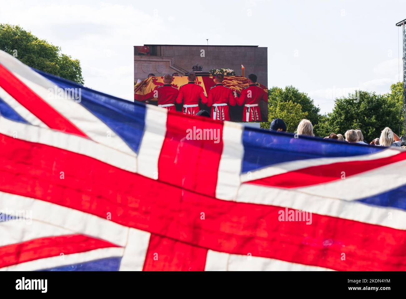 Ein Paar mit einer Union Jack-Flagge, während sie die Live-Übertragung des Sarges Ihrer Majestät der Königin beobachten, der von einem Militärzug aus Buckingh genommen wird Stockfoto