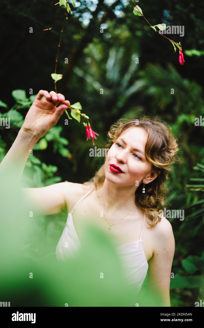 Frau im rosafarbenen Gown bei einem Besuch in einem idyllischen Garten Stockfoto