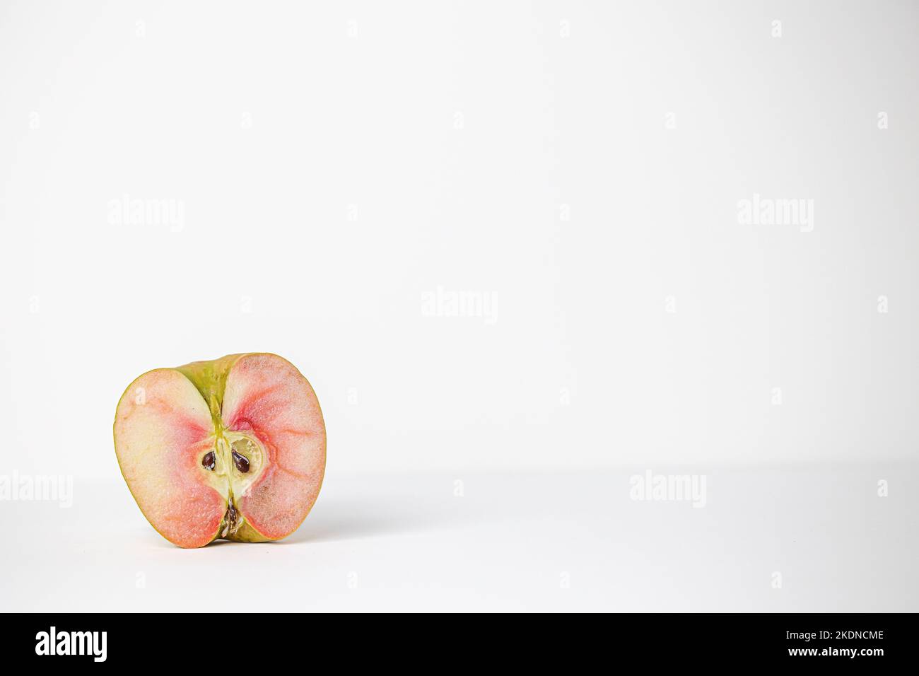 Eine Hälfte eines einzelnen lucy glo Apfels auf weißem Hintergrund Stockfoto
