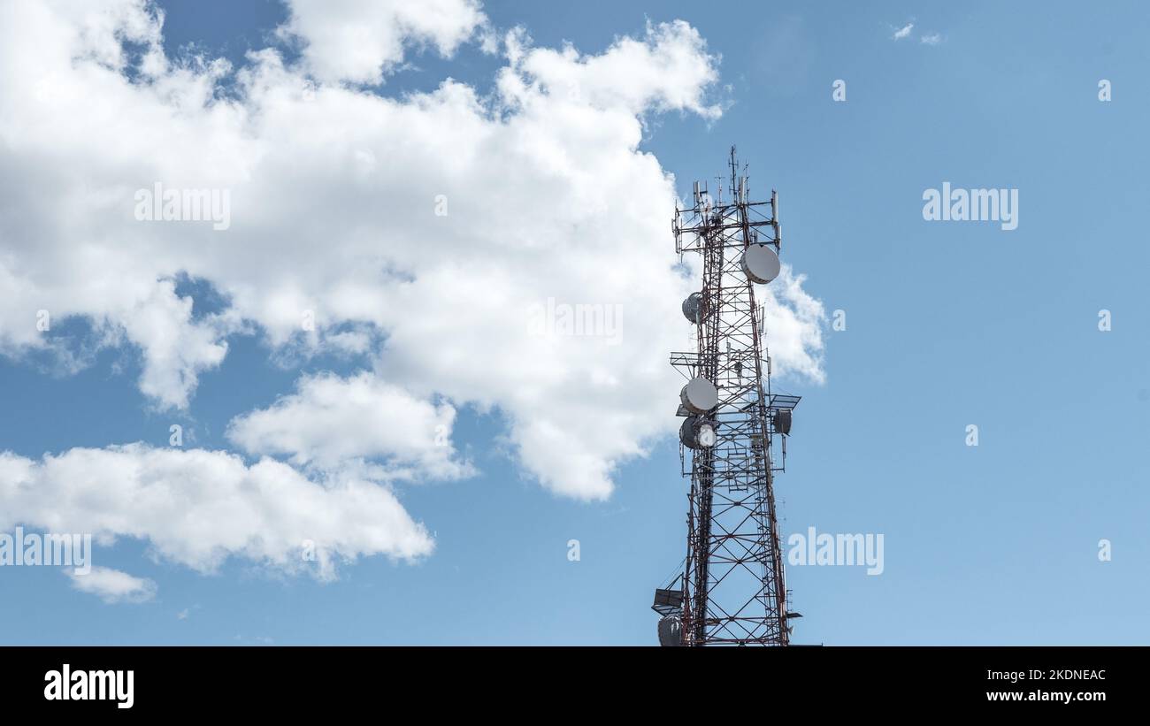 Radio-, Kommunikations- und Zelltürme am blauen Himmel mit Wolkenhintergrund. Satellitenschüssel Telecom-Netzwerk bei Sonnenuntergang Kommunikationstechnologie-Netzwerk. Stockfoto