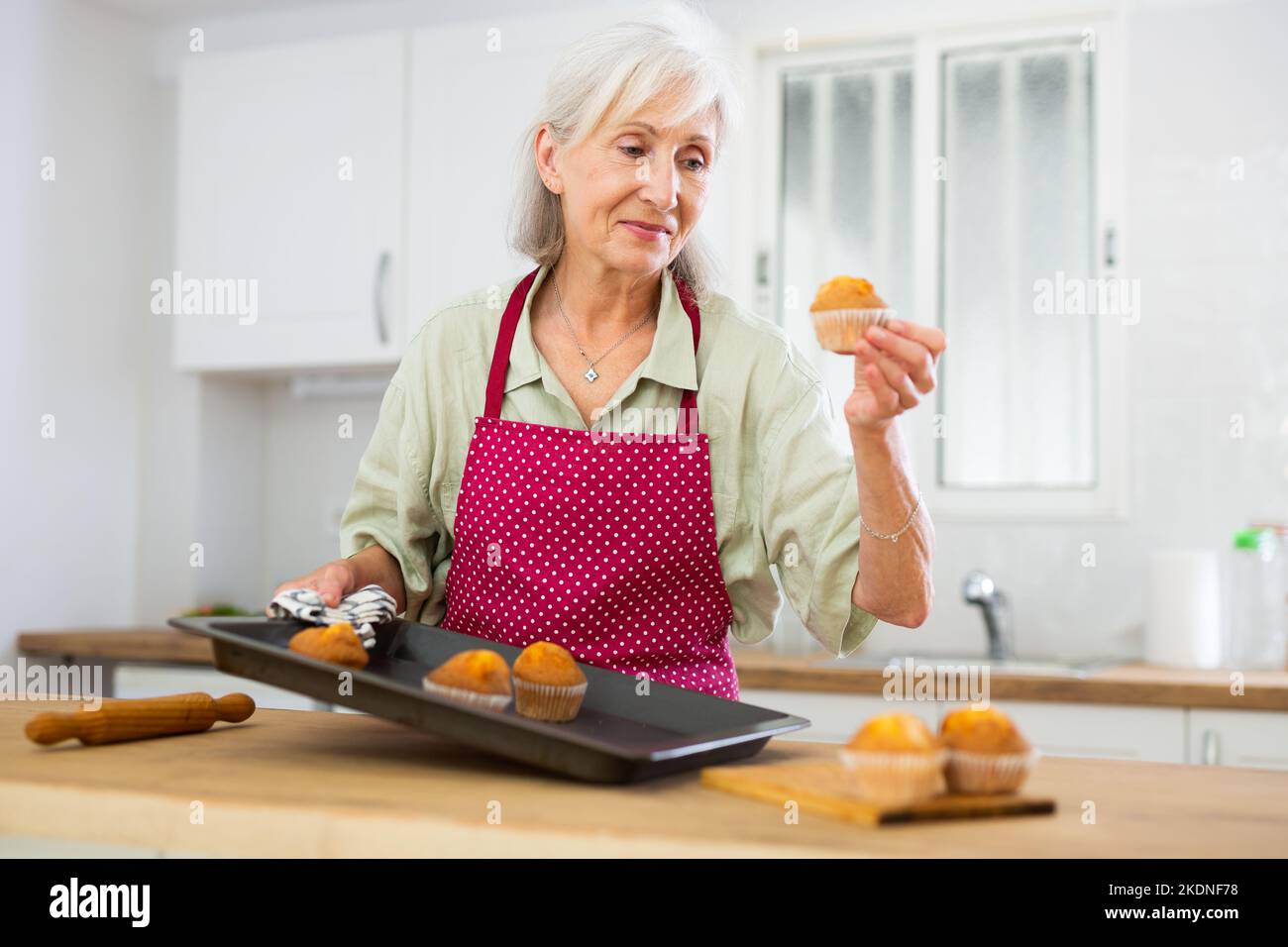 Reife Frau, die zu Hause VanilleMuffins backt Stockfoto