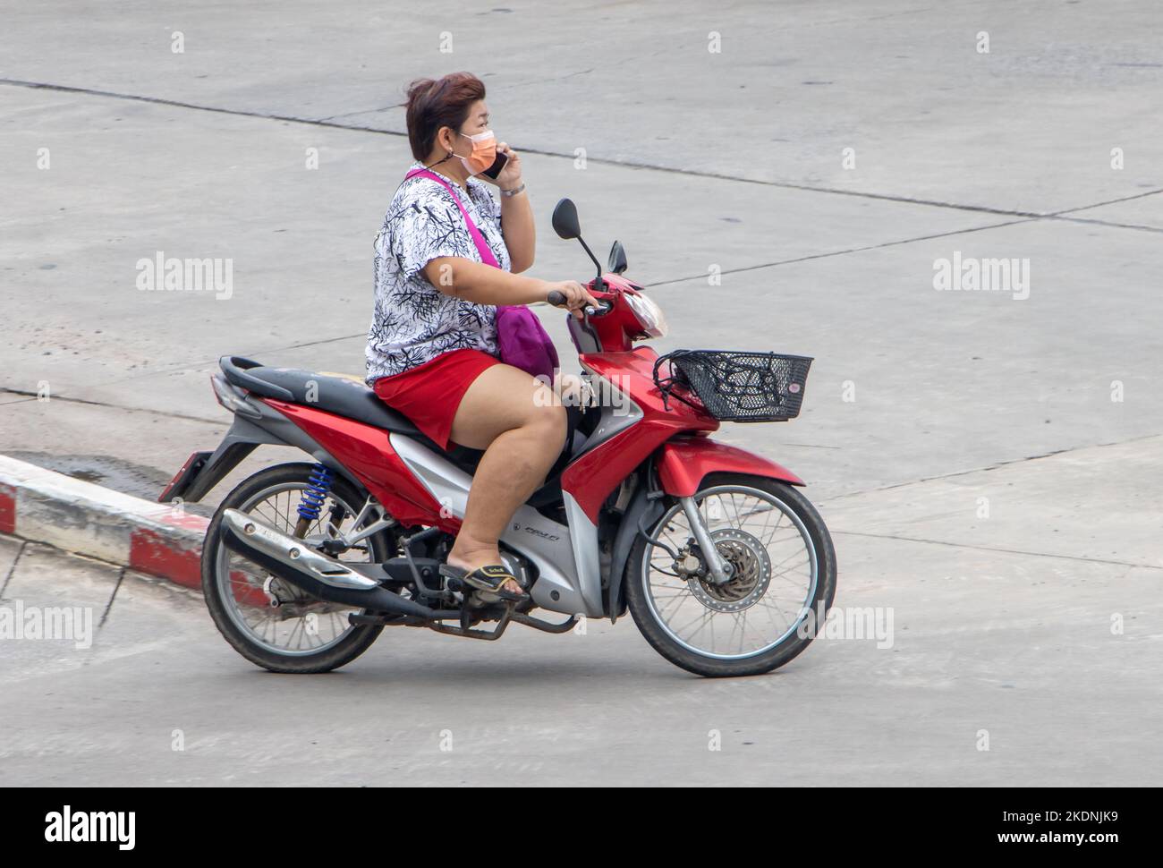 SAMUT PRAKAN, THAILAND, SEP 28 2022, Eine Frau ruft von einem Mobiltelefon aus an, während sie ein Motorrad fährt Stockfoto