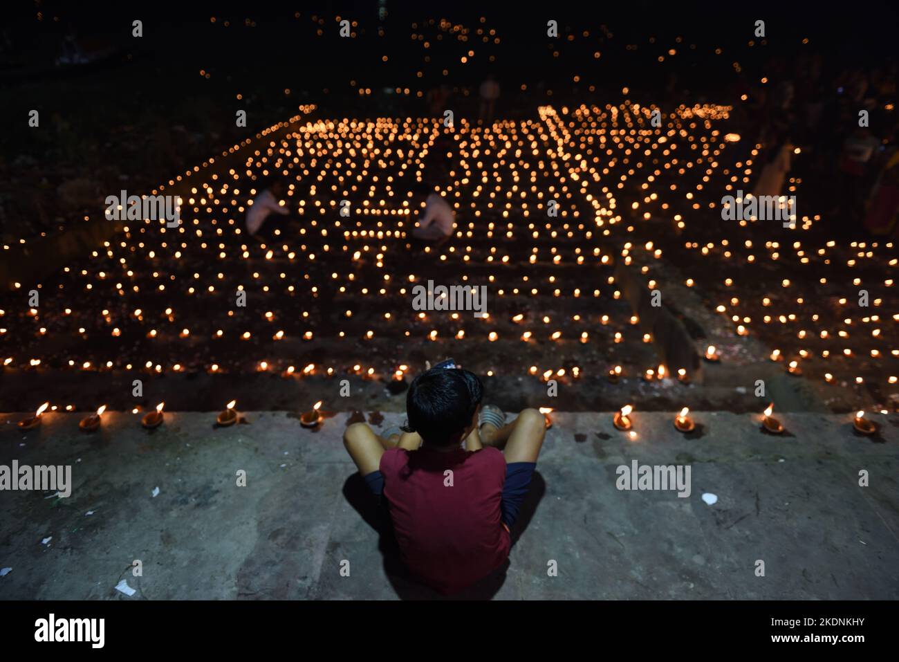Kalkutta, Indien. 7.. November 2022. Ein Junge sitzt auf einem beleuchteten Ghat auf Ganga 