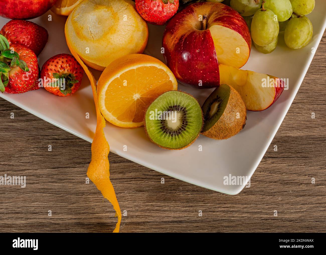 Stillleben von bunten tropischen Früchten auf einem quadratischen Teller auf einer hölzernen Oberfläche. Stockfoto