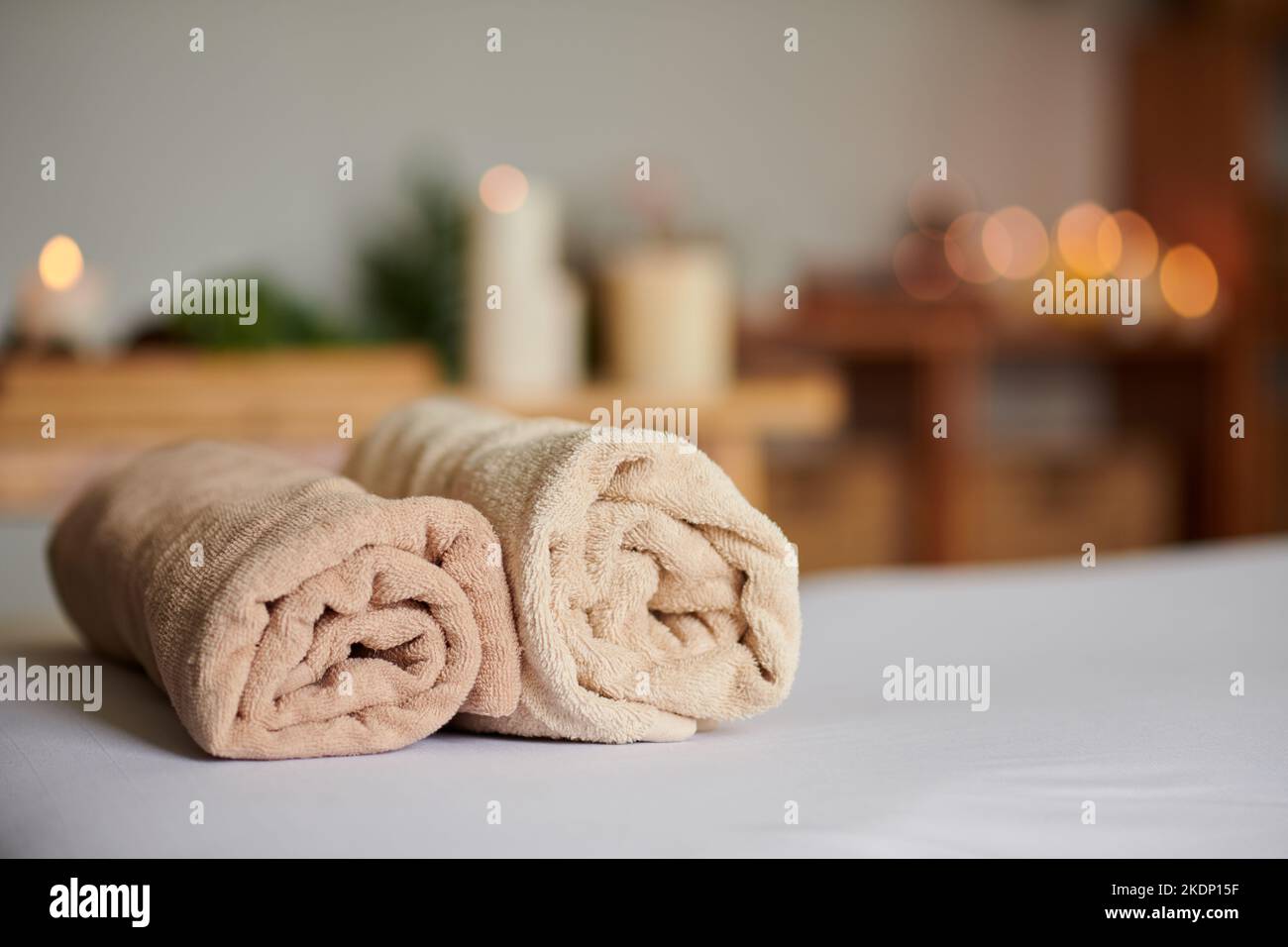 Zwei zusammengerollte weiche Handtücher auf dem Bett im Spa-Salon Stockfoto